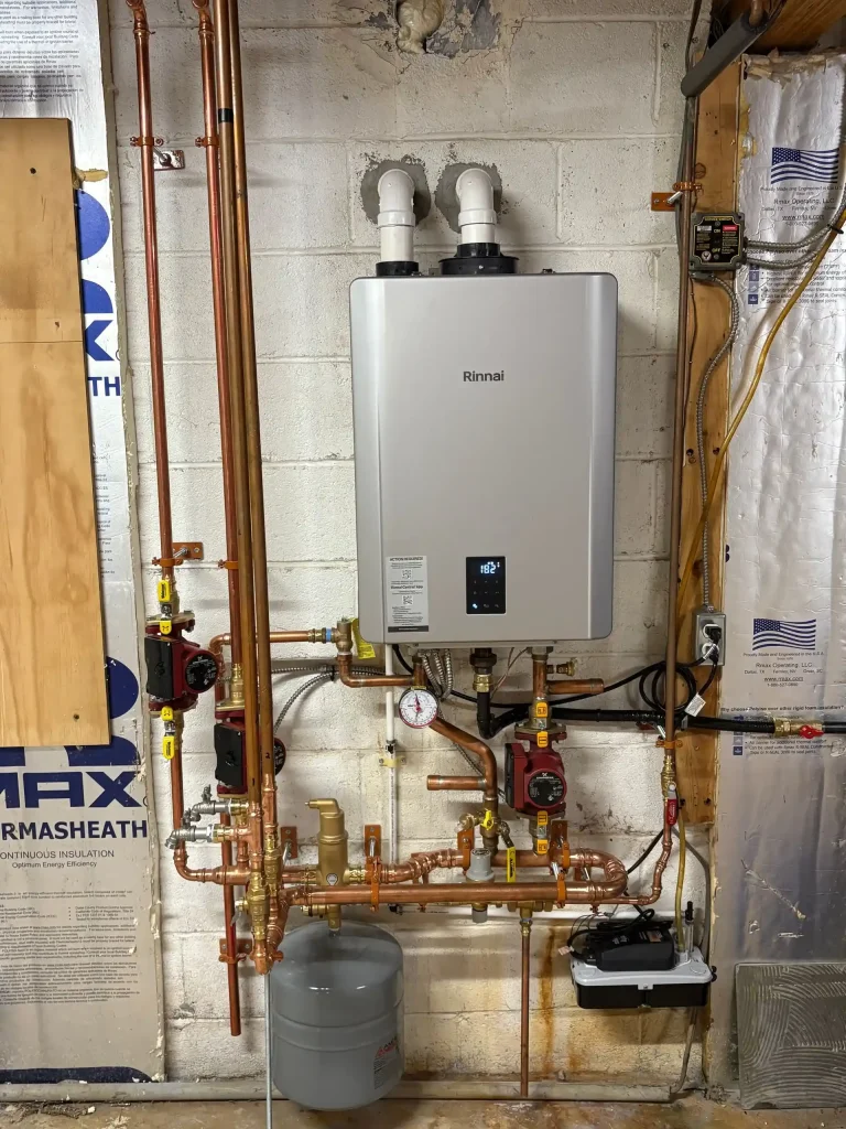 Rinnai wall-mounted heating unit connected to copper piping, circulation pumps, controls, and an expansion tank.